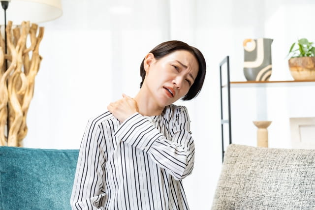 肩をおさえる女性